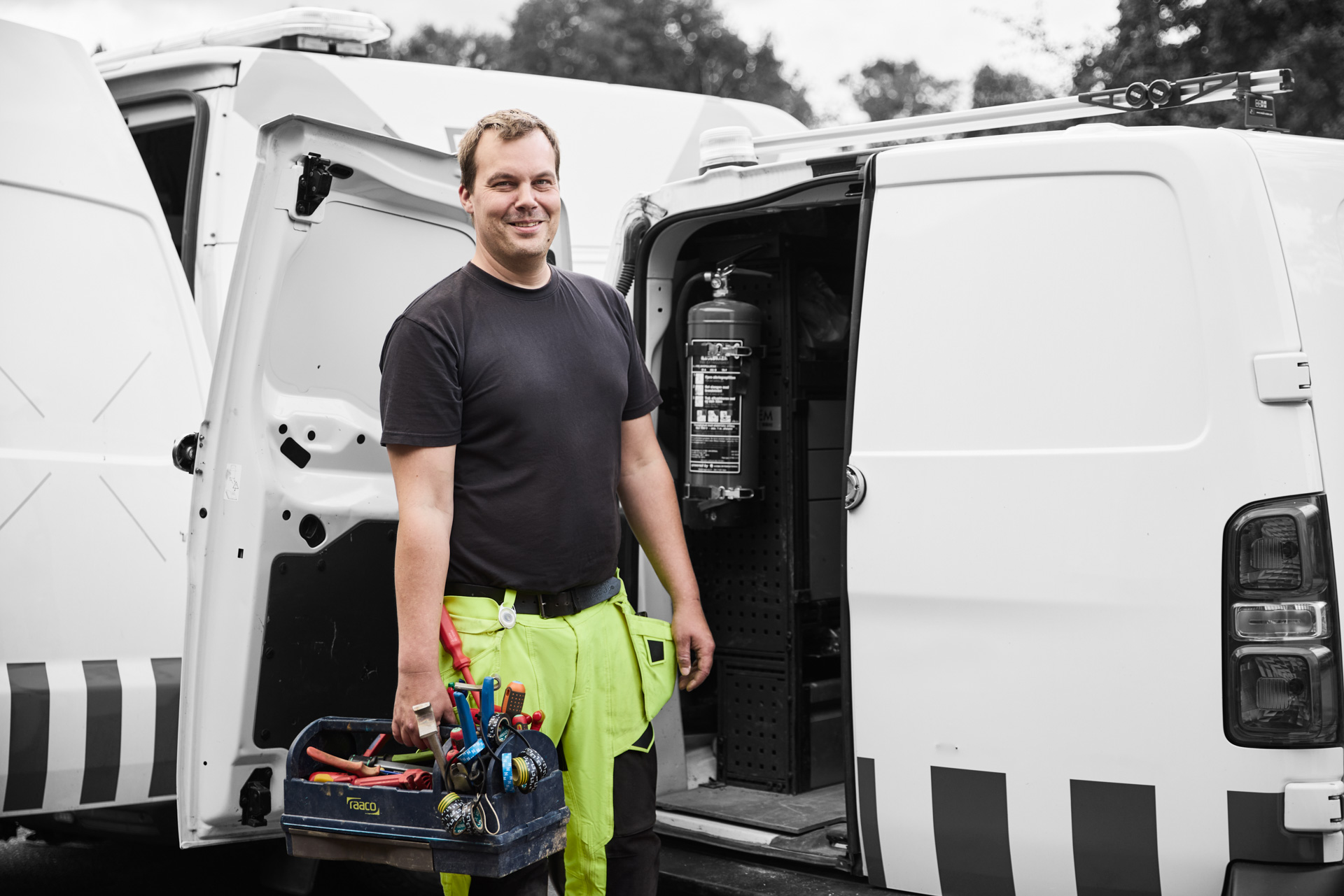 Forsyningsoperatør med værktøjskasse foran bil