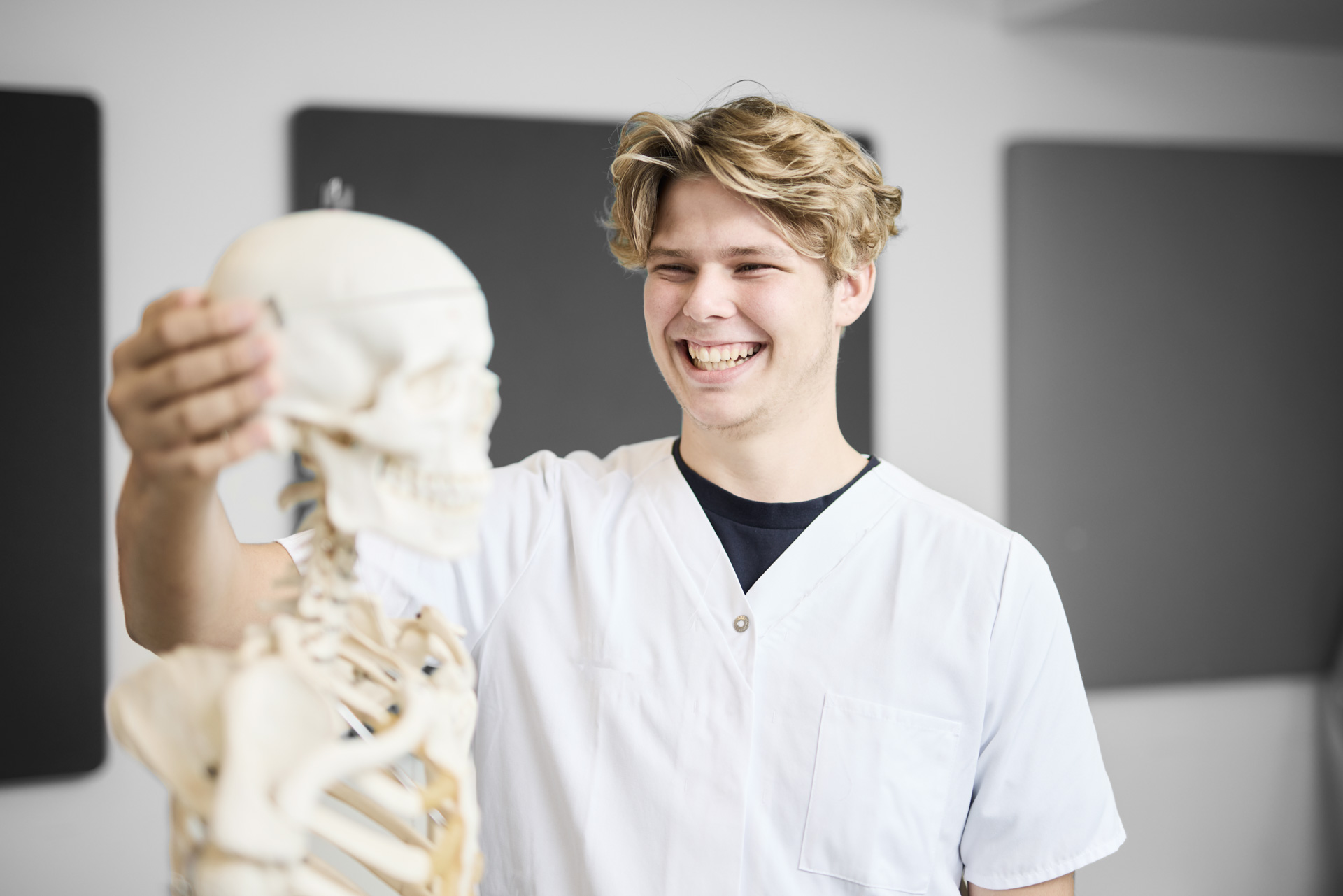 ZBC SOSU-uddannelser i Slagelse - Social- og sundhedsassistent står foran skelet og øver anatomi