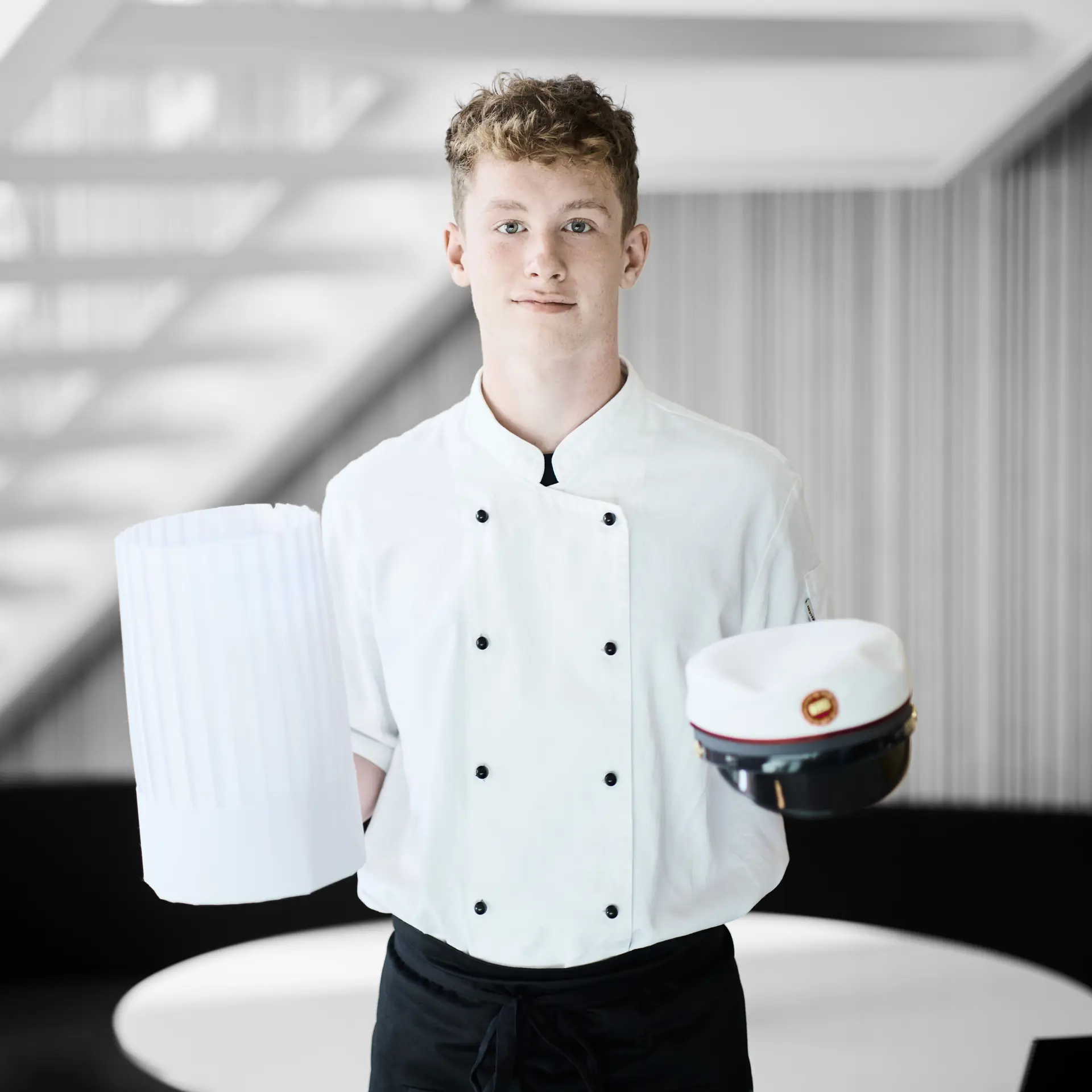 Kok står med kokkehue og studenterhue