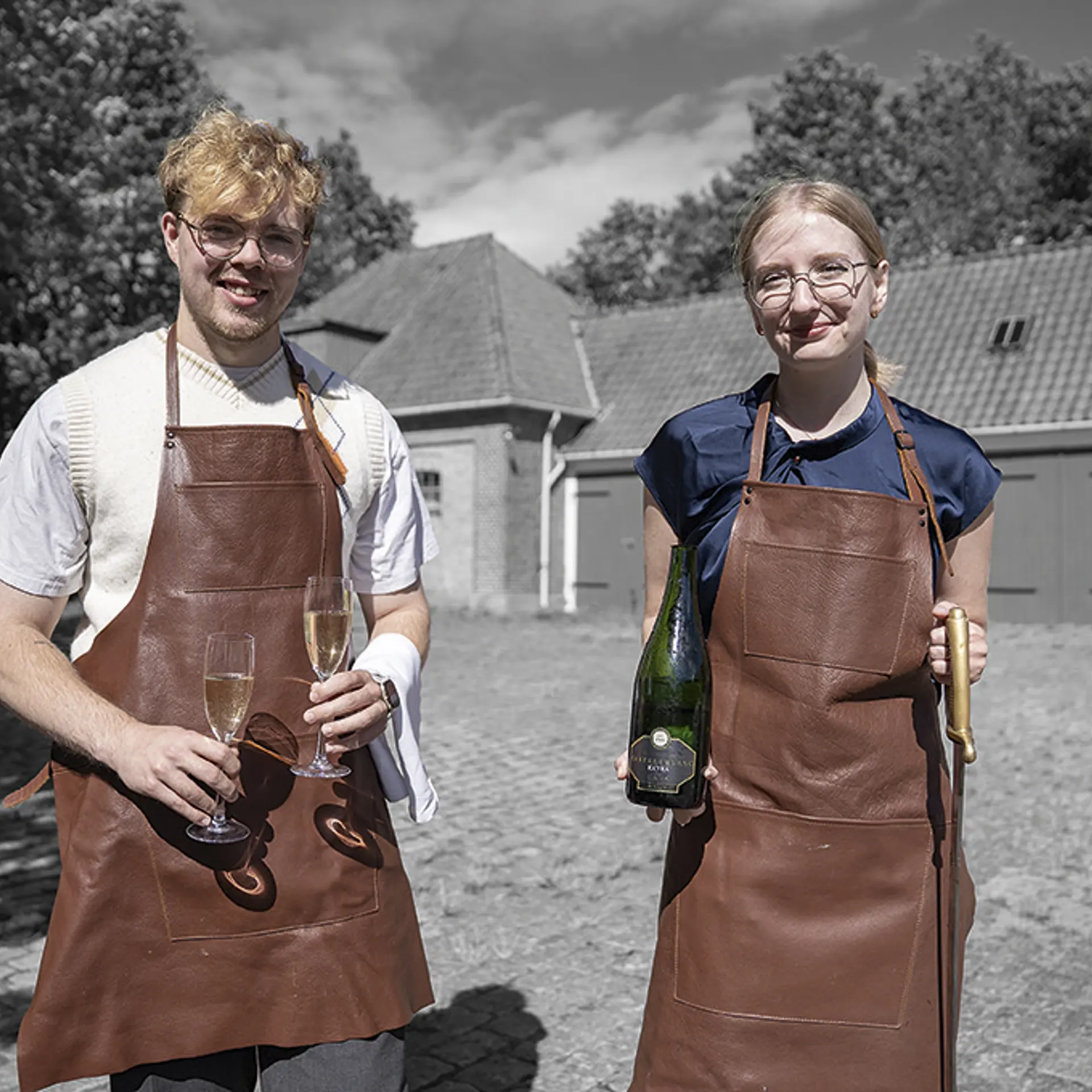 To elever på tjeneruddannelsen står med champagne og glas
