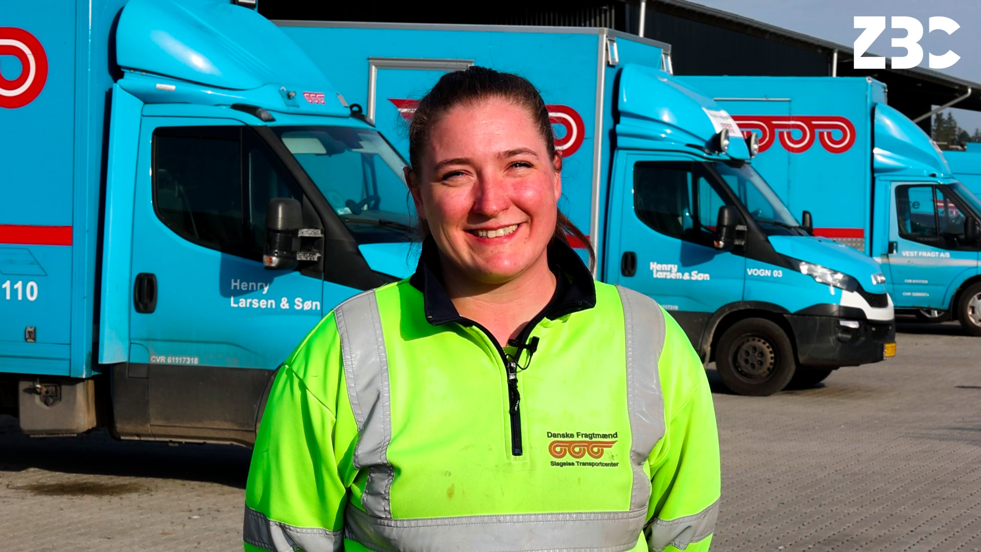 Jeanett fra vejgodstransportuddannelsen står foran lastbiler på sin læreplads