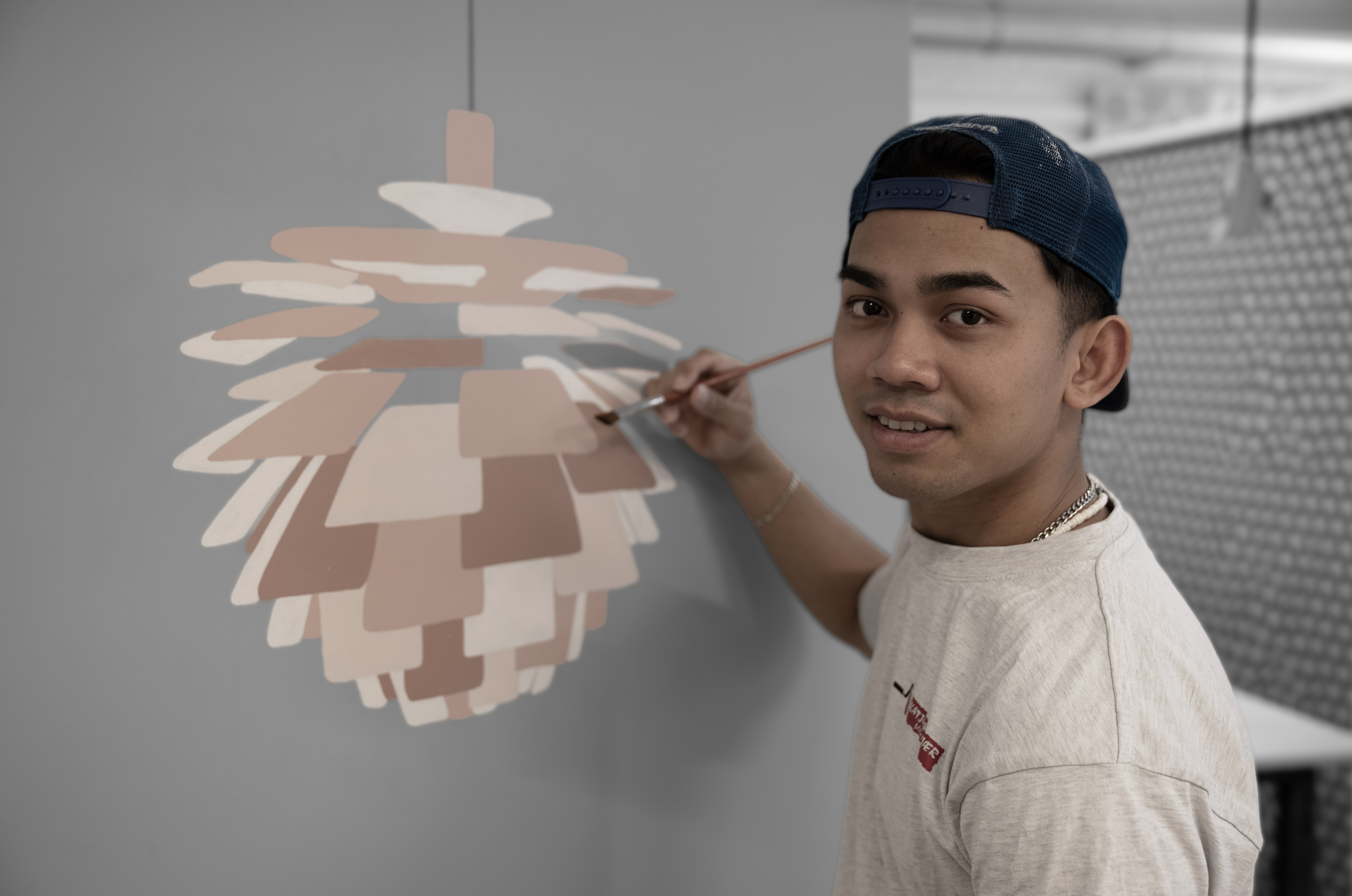 Bygningsmalerelev maler lampe på væg