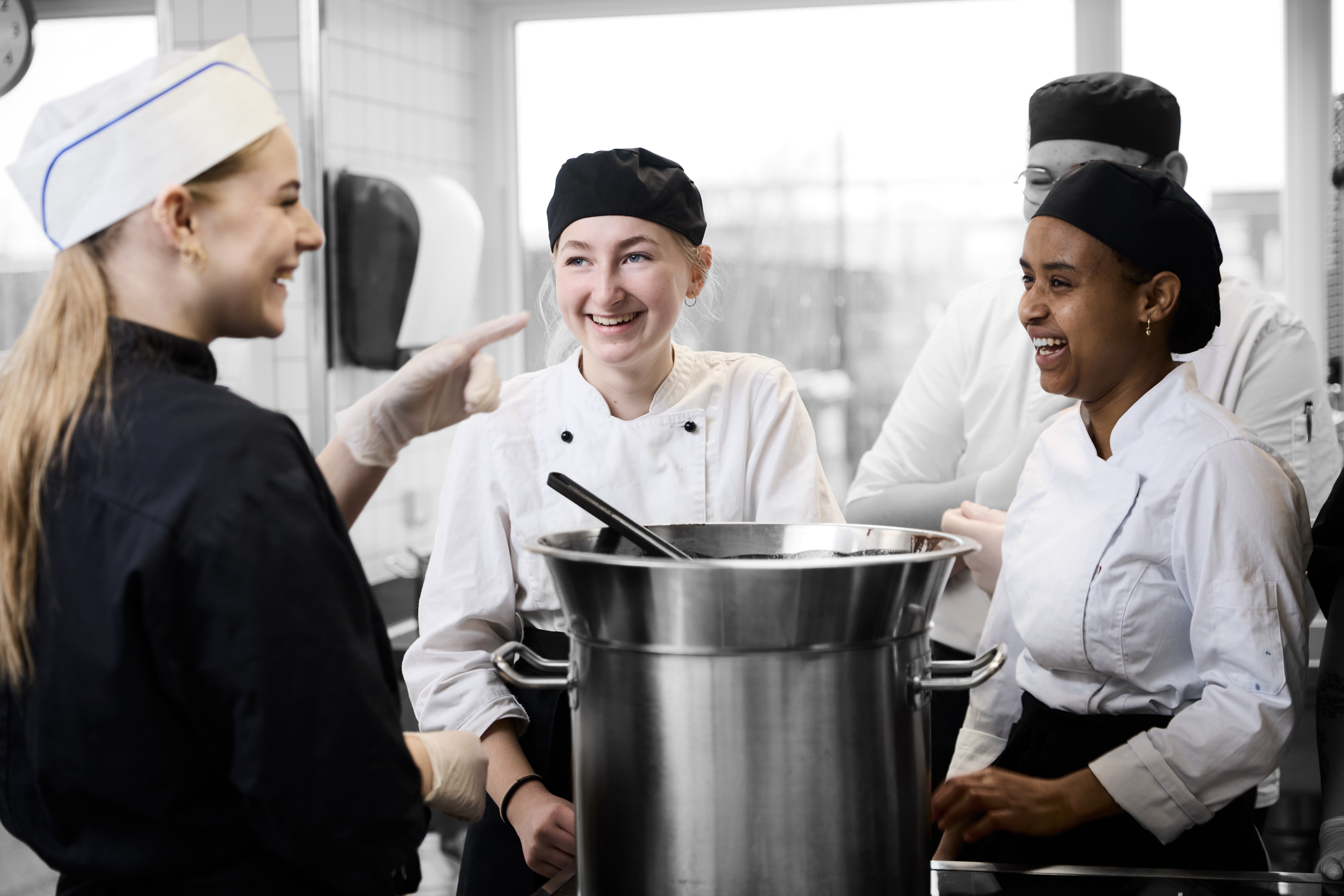 Ernæringsassistenter i køkkenet, hvor de tempererer chokolade ved en gryde 