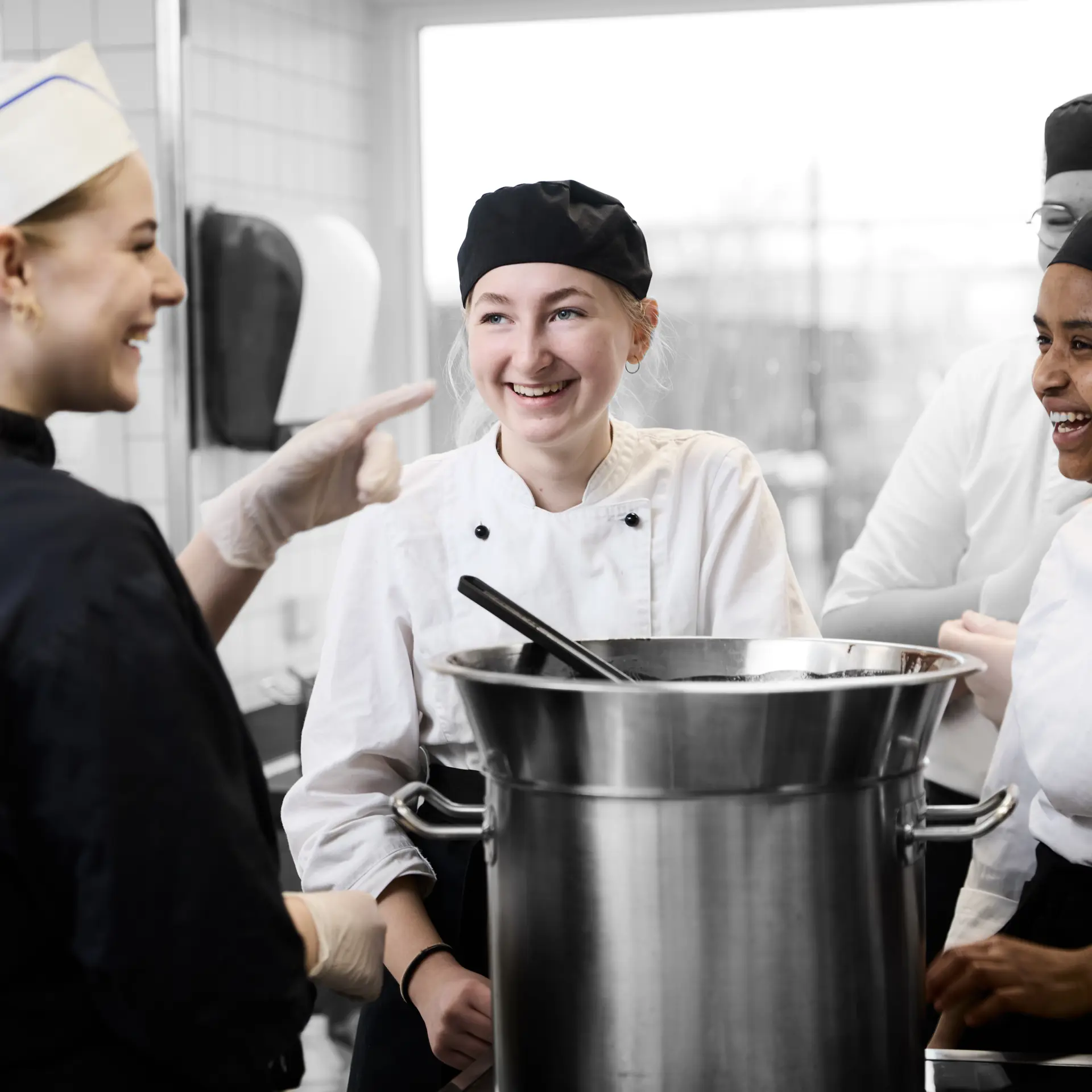 Ernæringsassistenter i køkkenet, hvor de tempererer chokolade ved en gryde