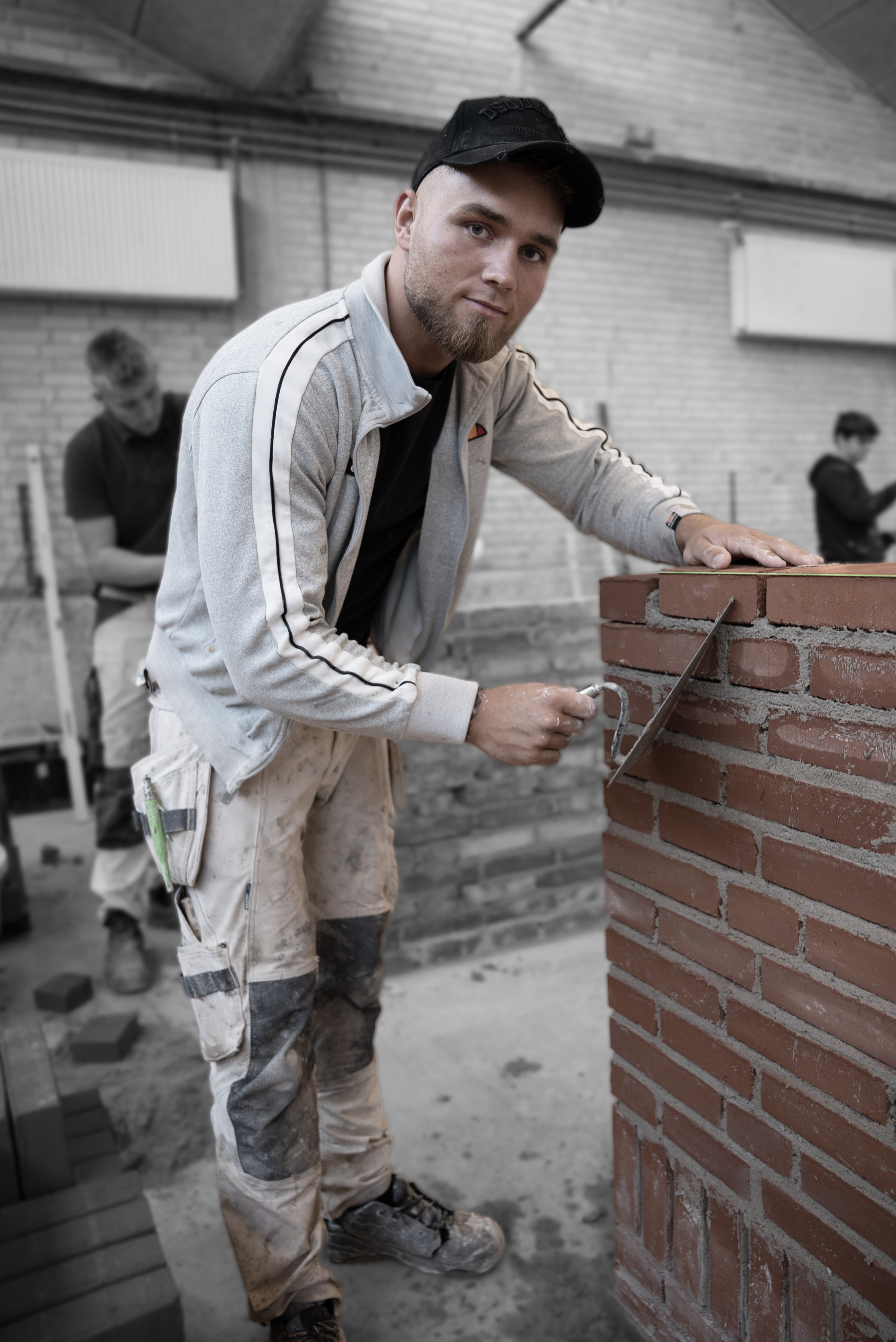 Elev på mureruddannelsen stabler mursten med mørtel