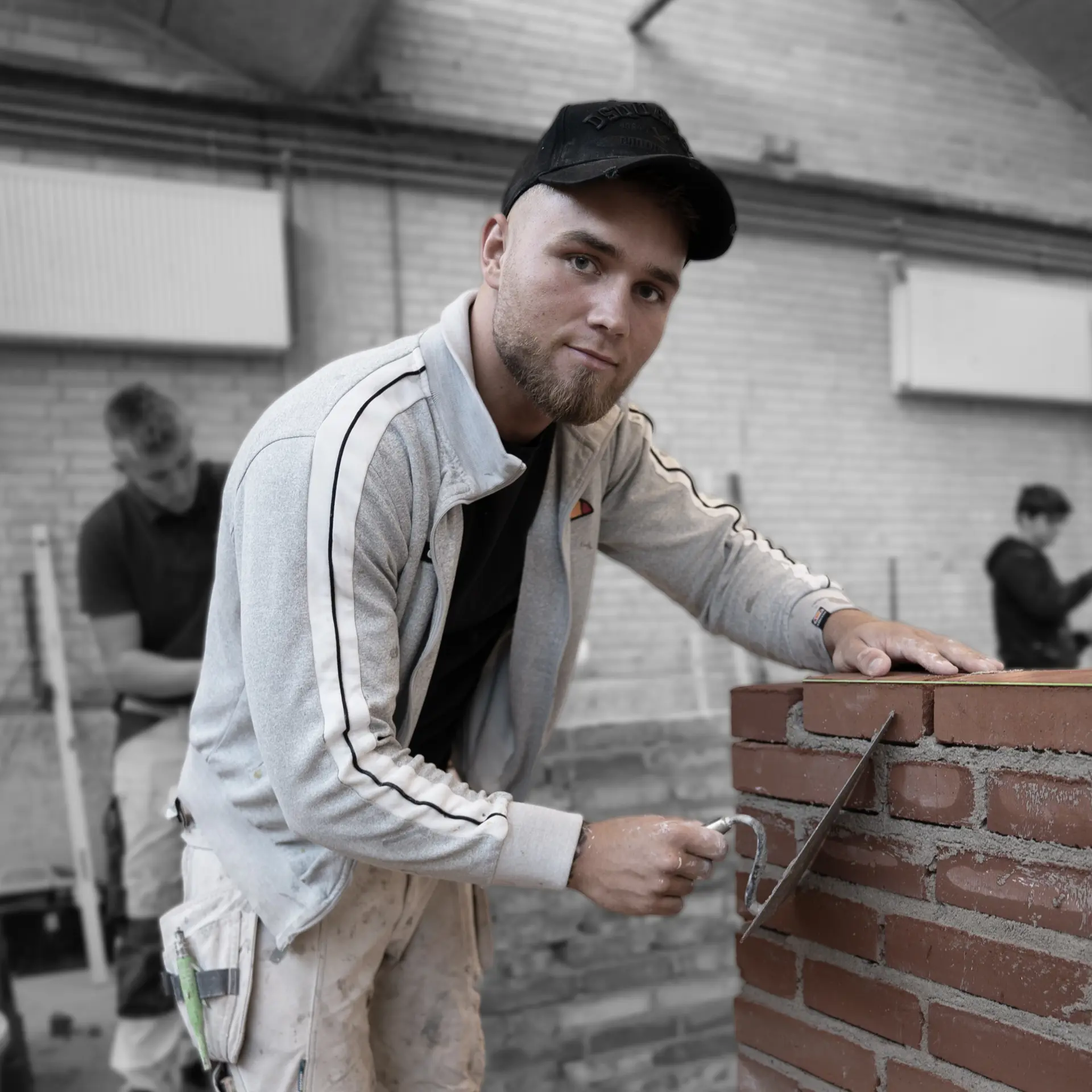 Elev på mureruddannelsen stabler mursten med mørtel