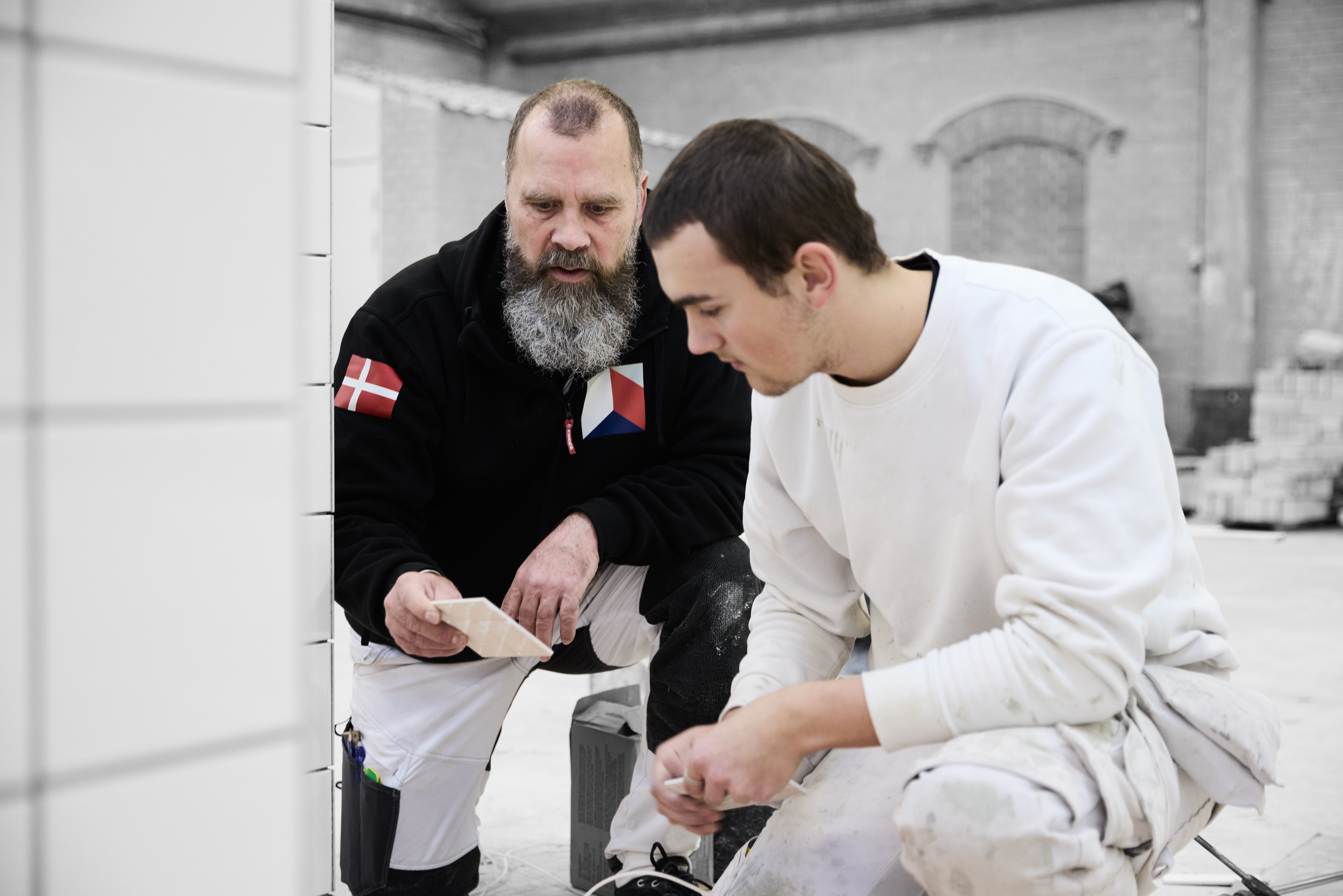 Murer-elev ser på flise sammen med faglærer