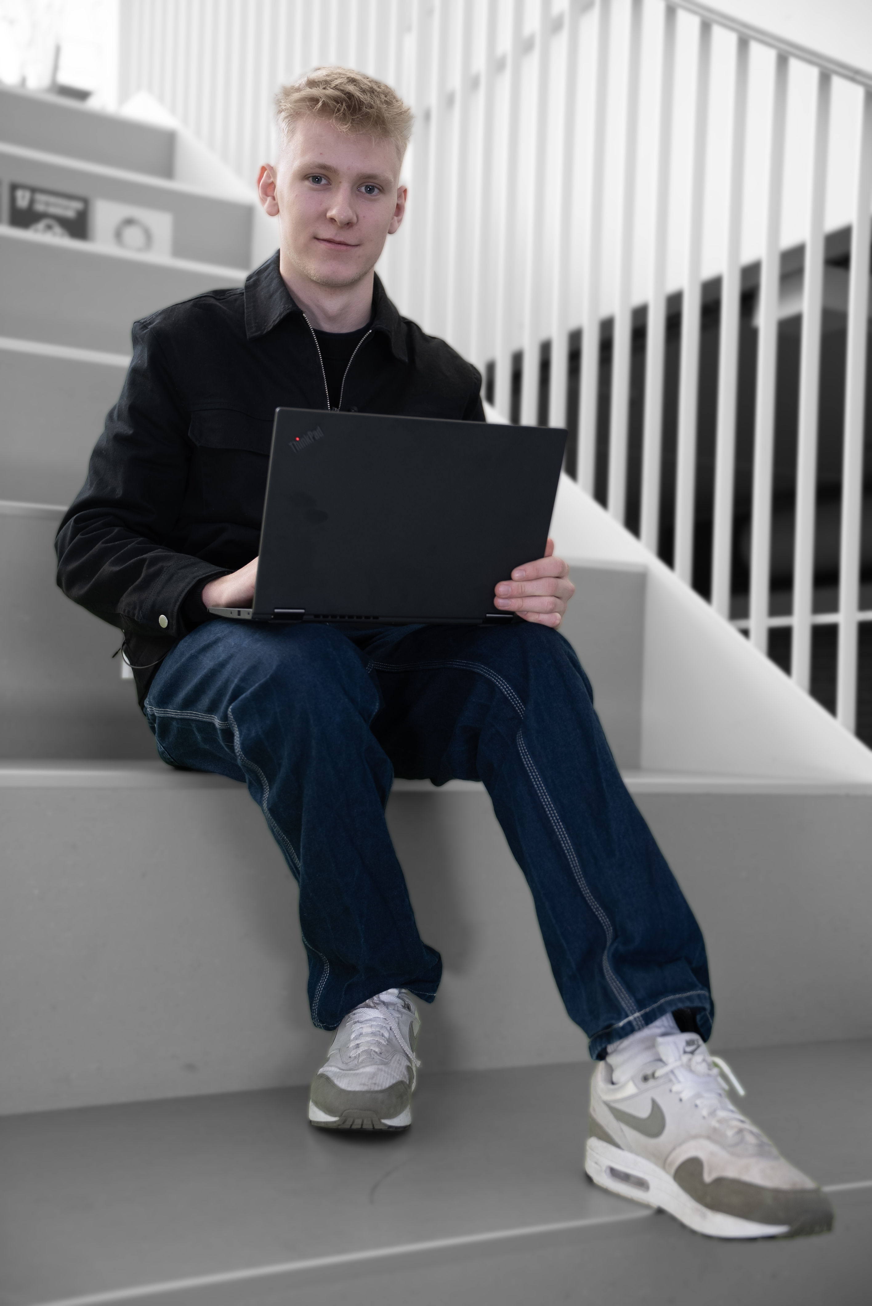 Elev på handelsuddannelsen sidder med computer på trappe