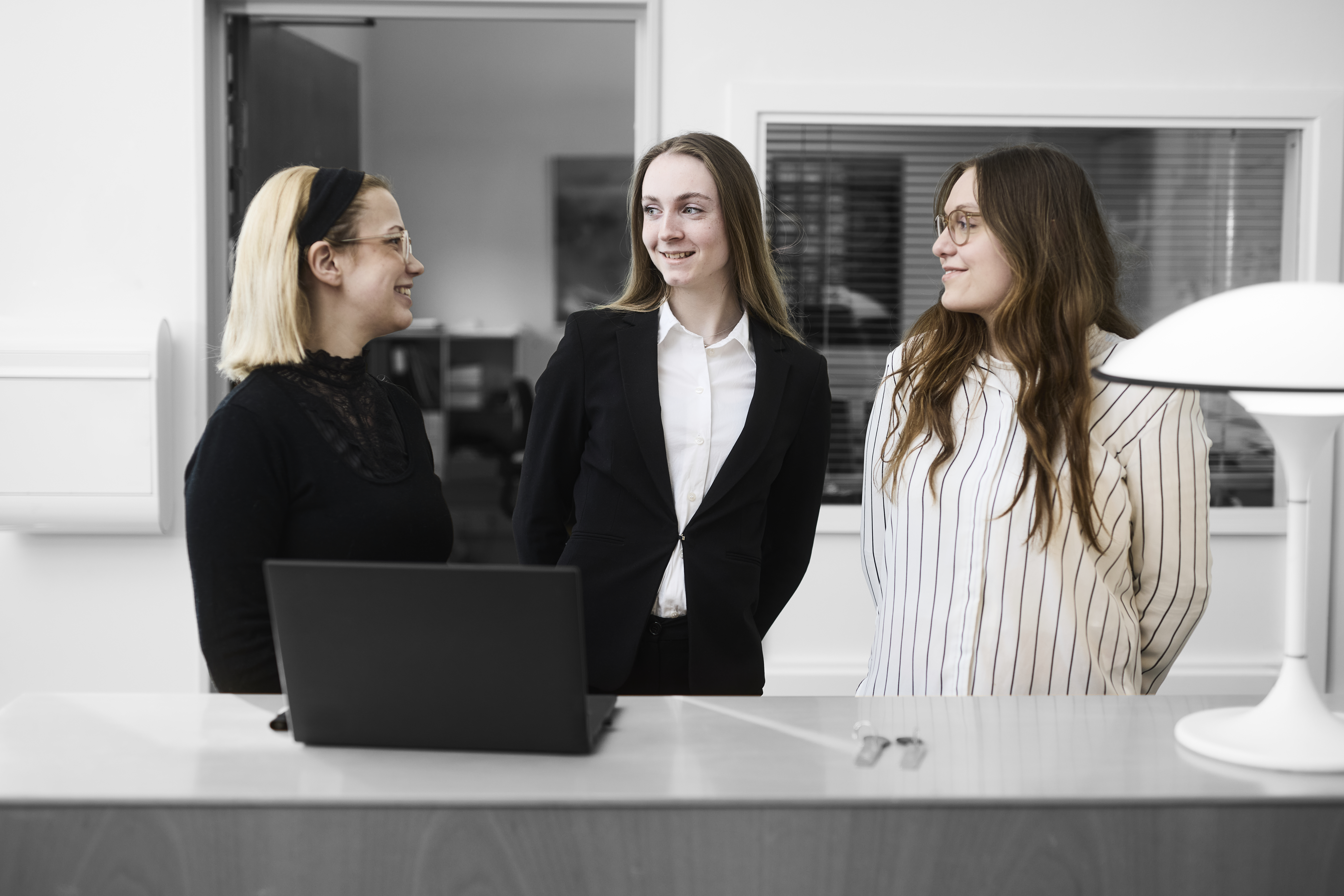 Receptionistelever smiler til hinanden, mens de står ved en skranke