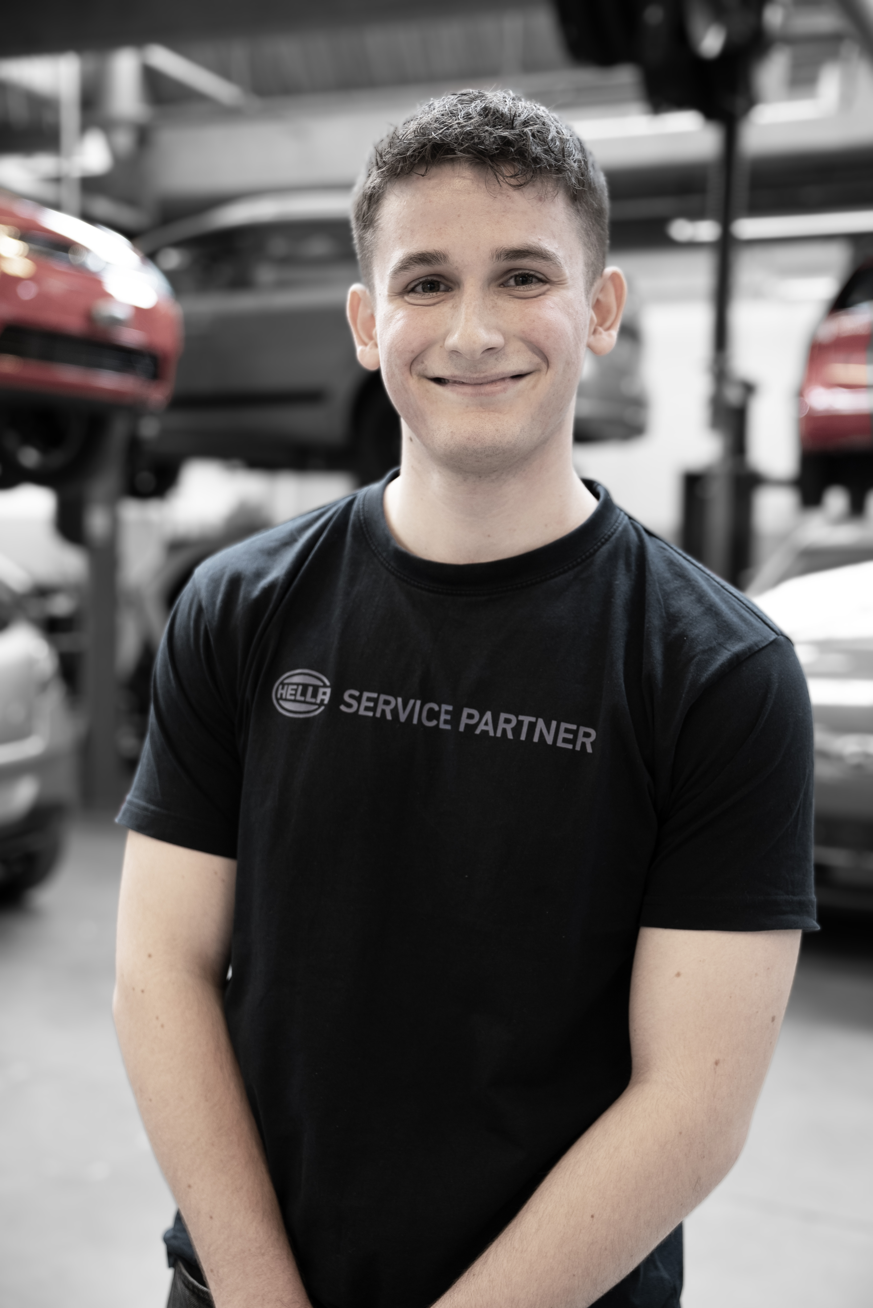 Elev på uddannelsen til mekaniker med biler i baggrunden