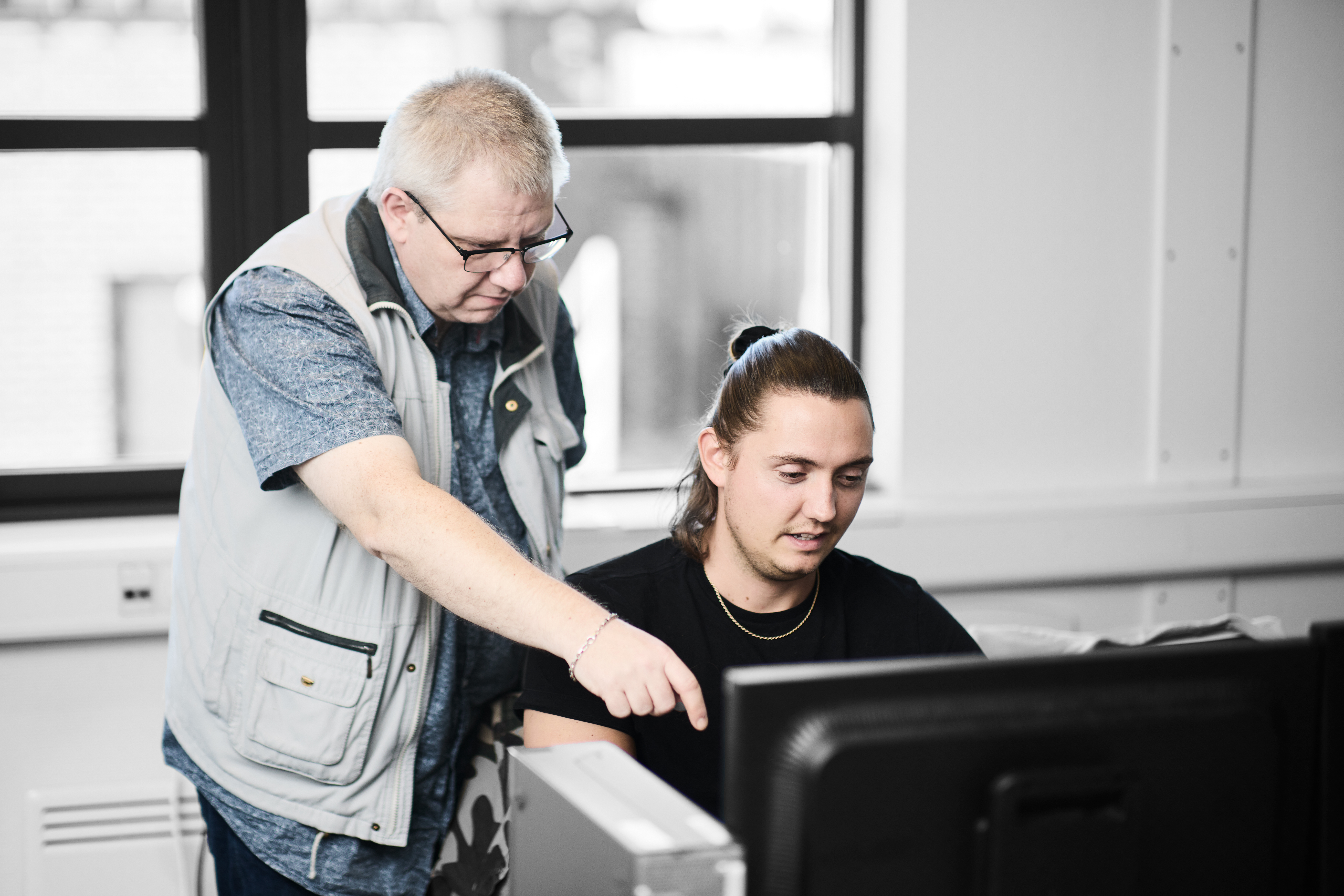 Datatekniker arbejder ved computer ved hjælp fra faglærer