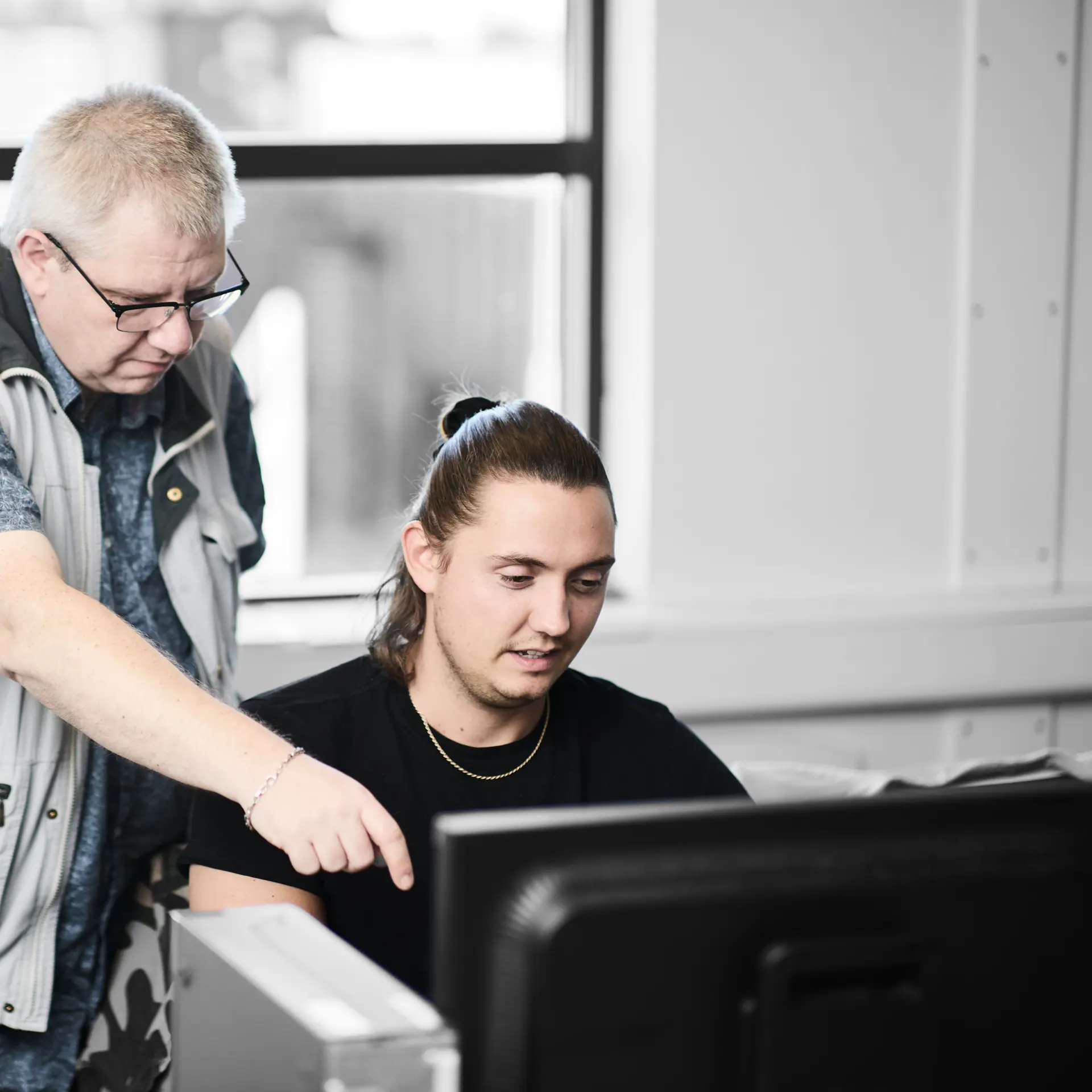 Datatekniker arbejder ved computer ved hjælp fra faglærer
