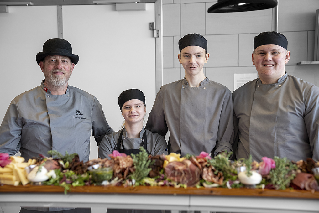 Underviser og elever på Gourmetslagteruddannelsen står i køkkenet