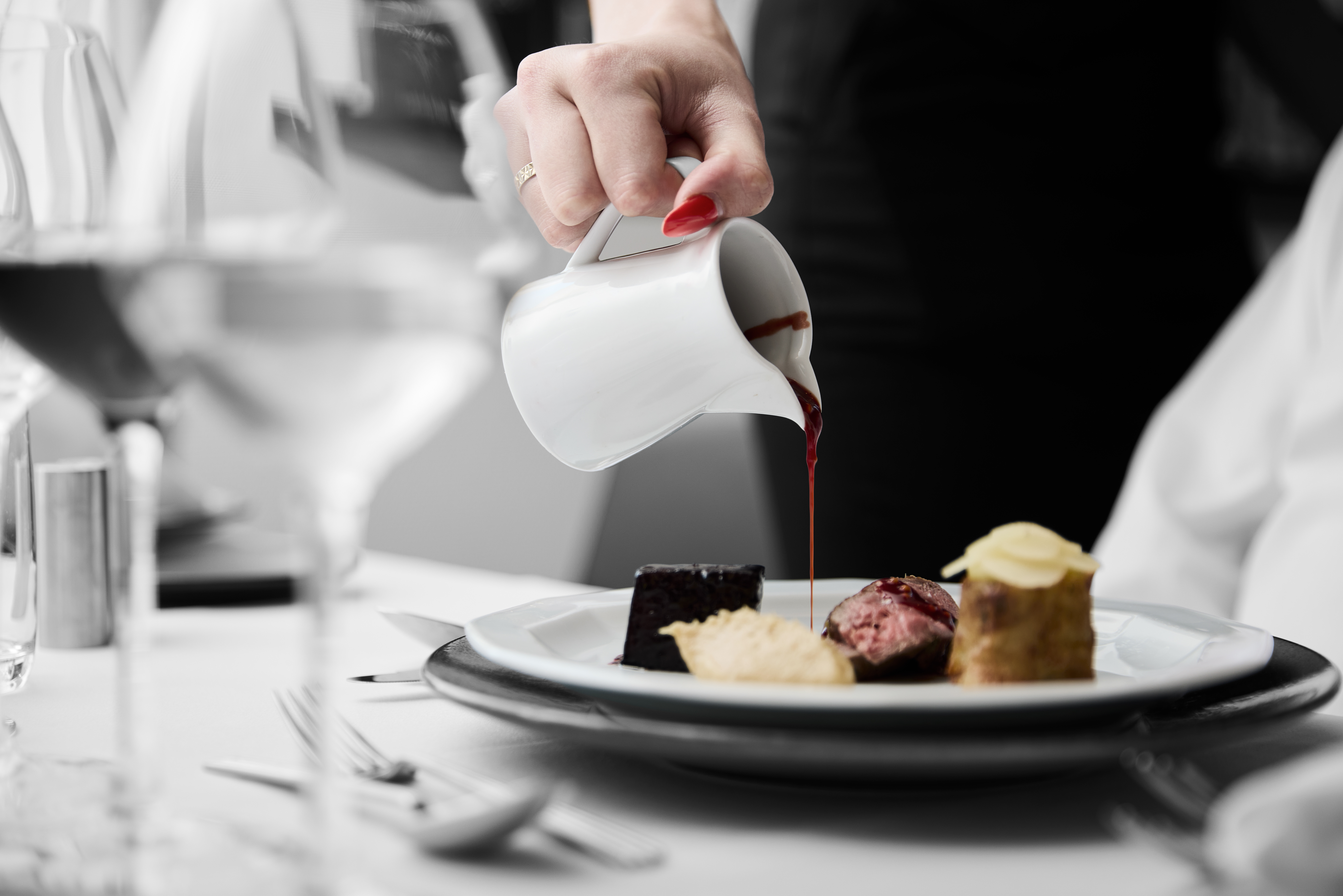 Tjener hælder en sovs over en anretning