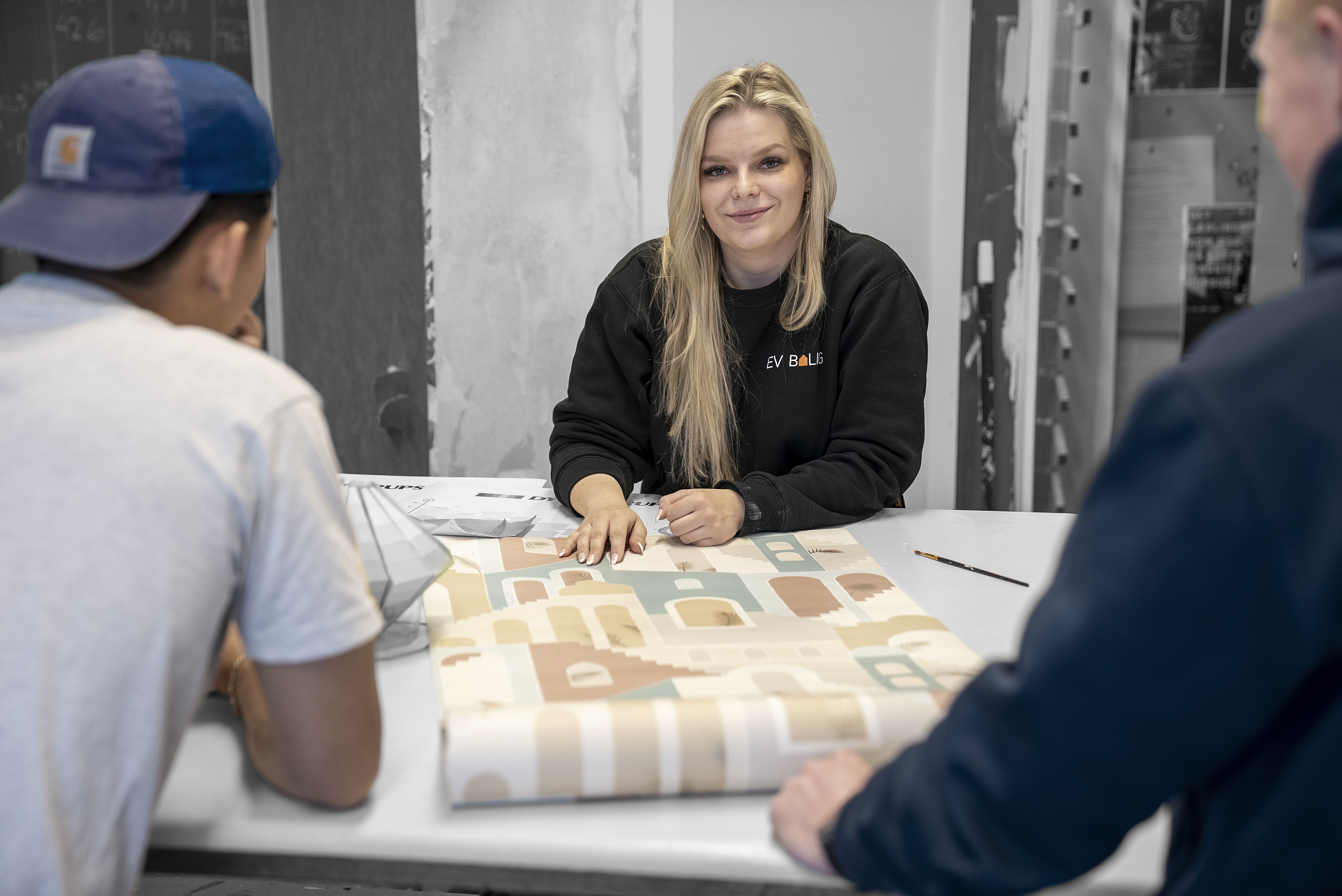 Elever på uddannelsen til bygningsmaler kigger på tapet