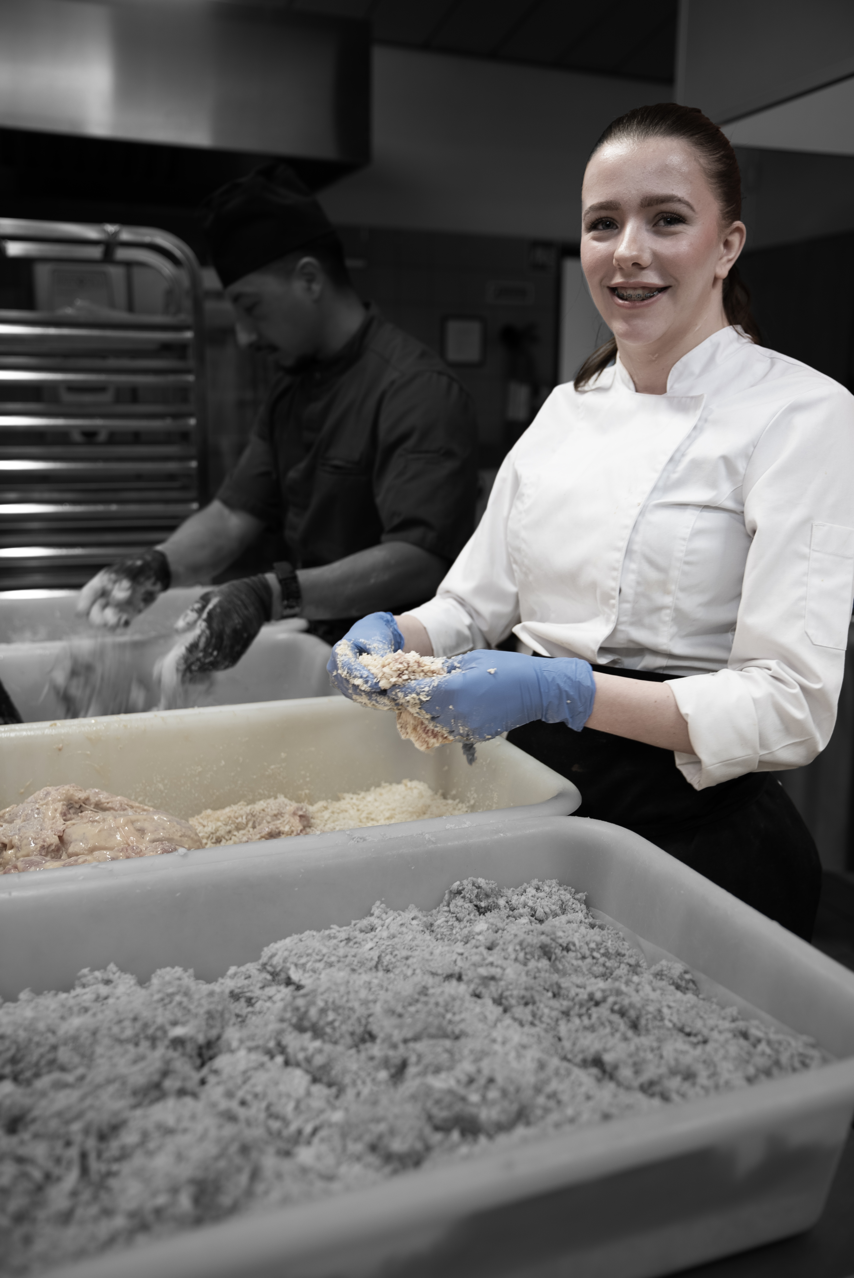 Elev på uddannelsen til ernæringsassistent arbejder med panering i køkkenet