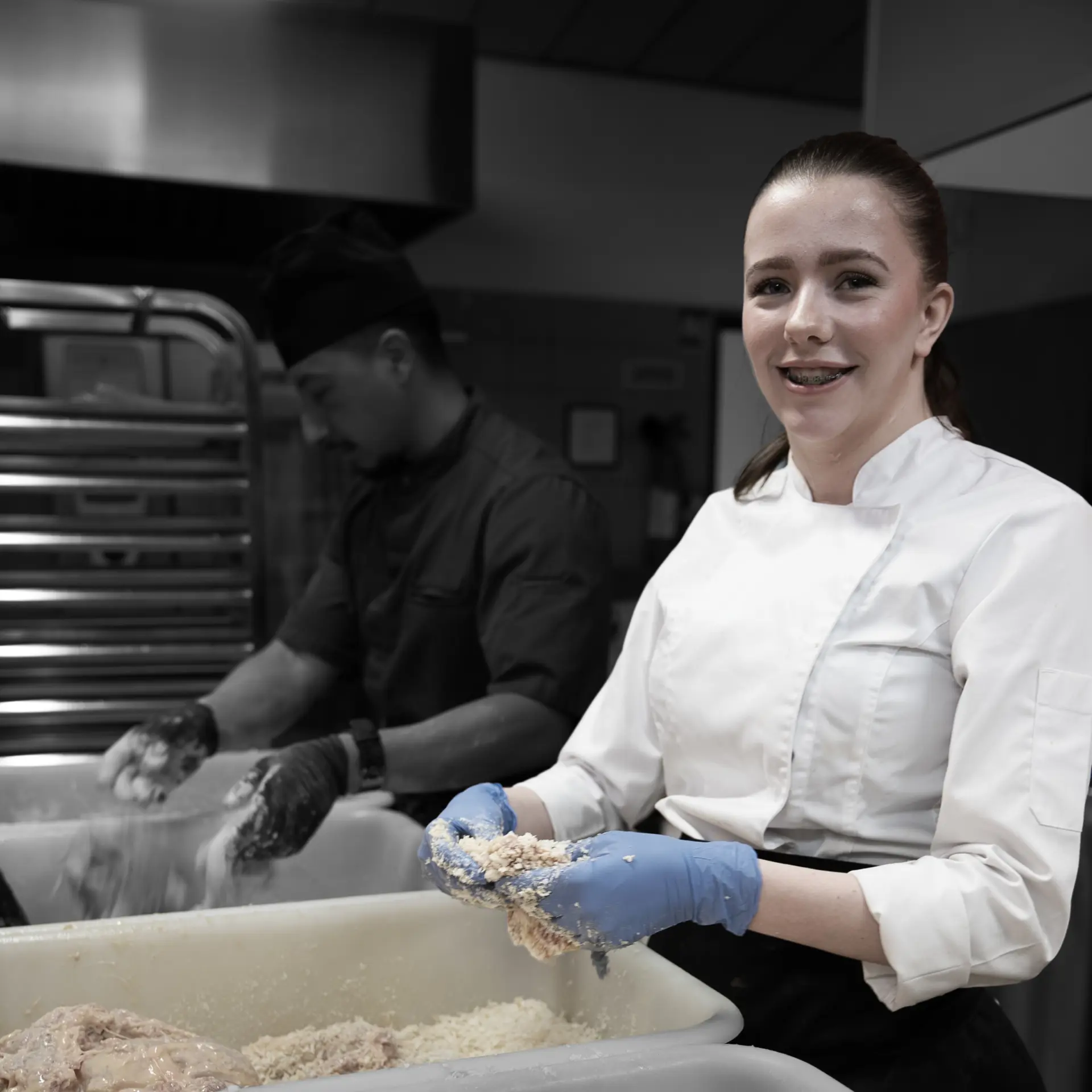 Elev på uddannelsen til ernæringsassistent arbejder med panering i køkkenet