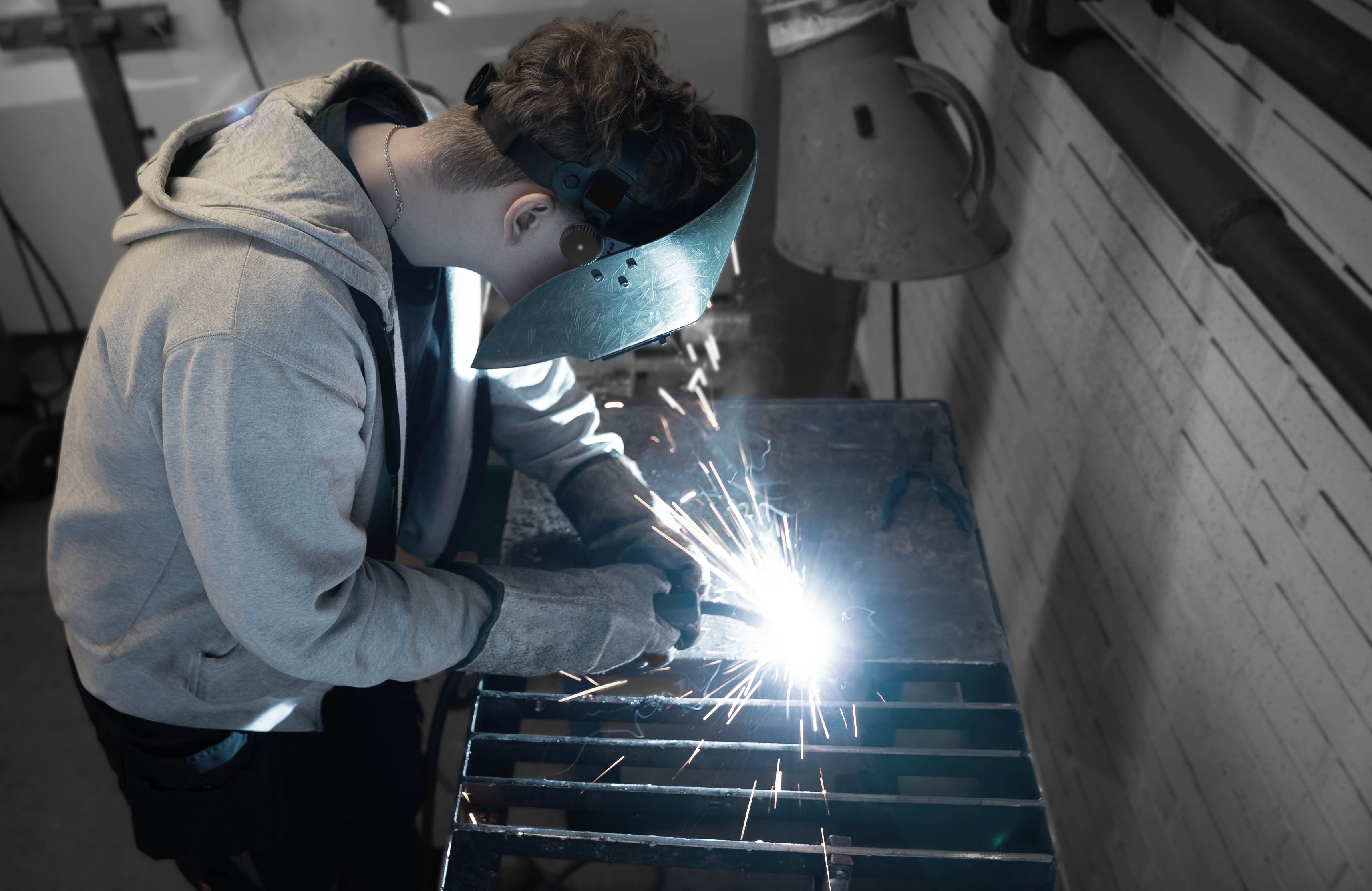 Elev på smedeuddannelsen svejser med beskyttelsesudstyr på