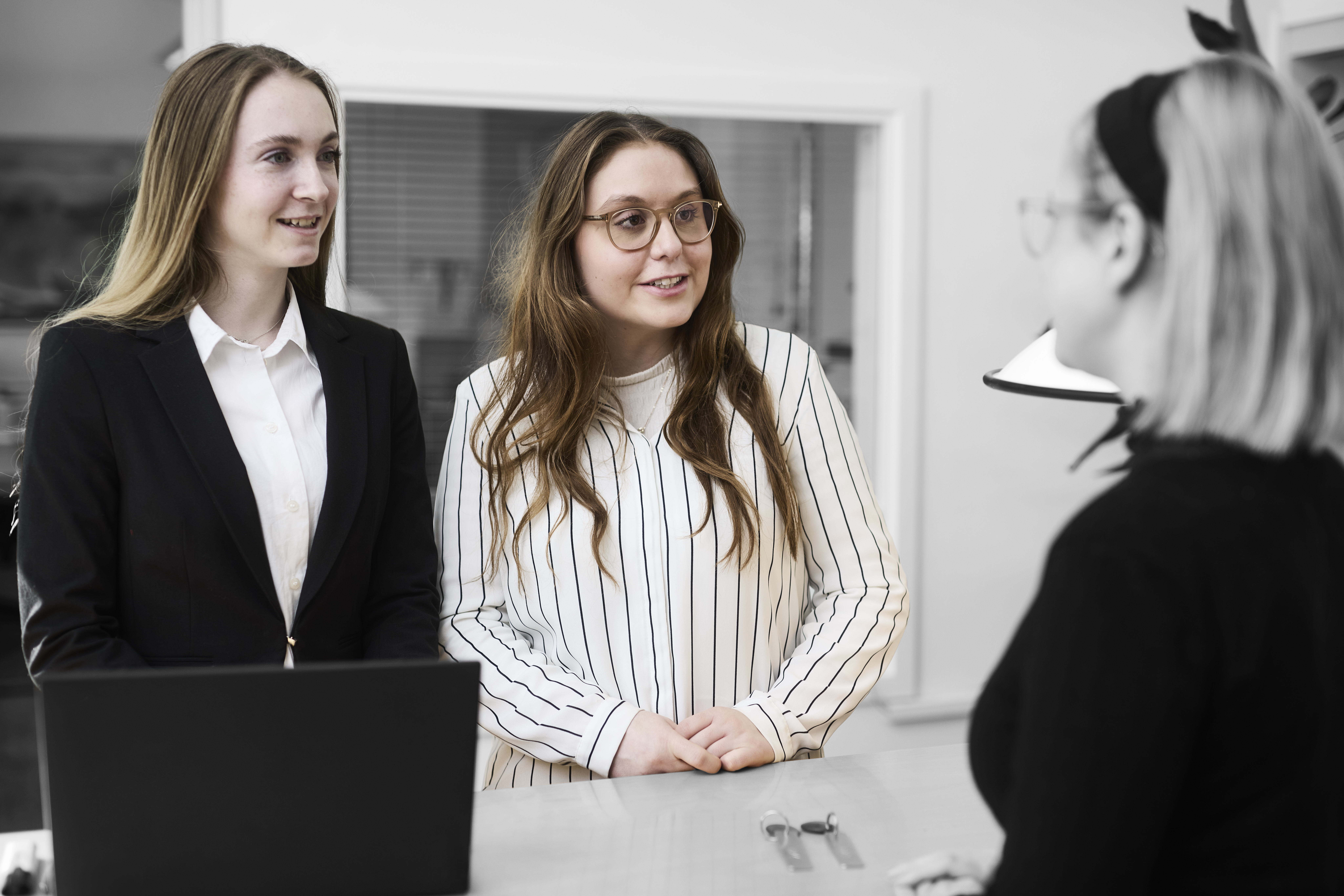 Receptionister ved skranke taler med kunde