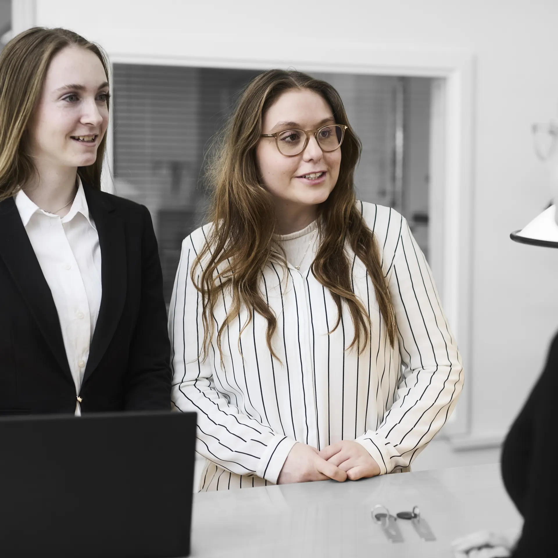 Receptionister ved skranke taler med kunde