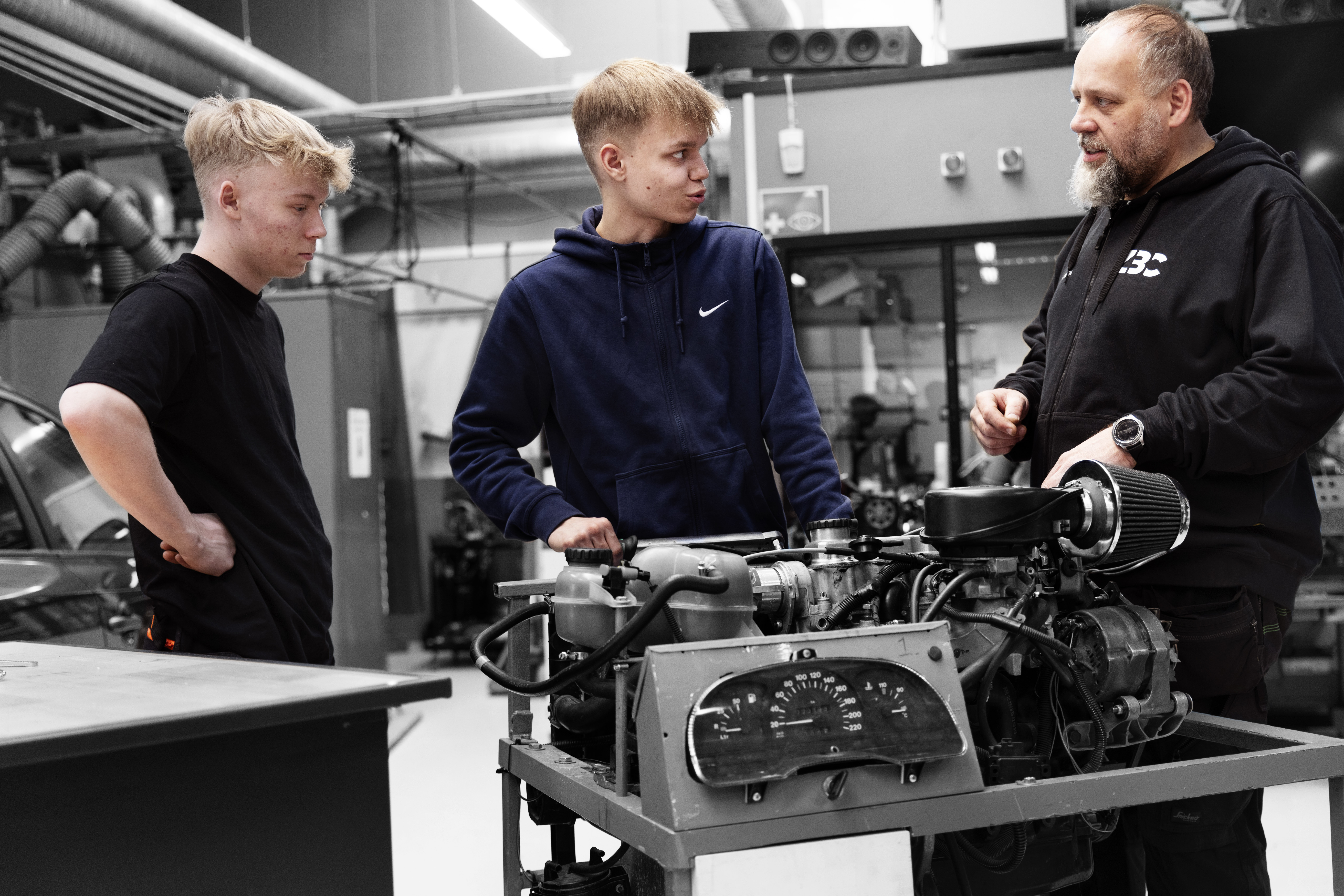 Personvognsmekaniker-elever og faglærer står sammen på værksted