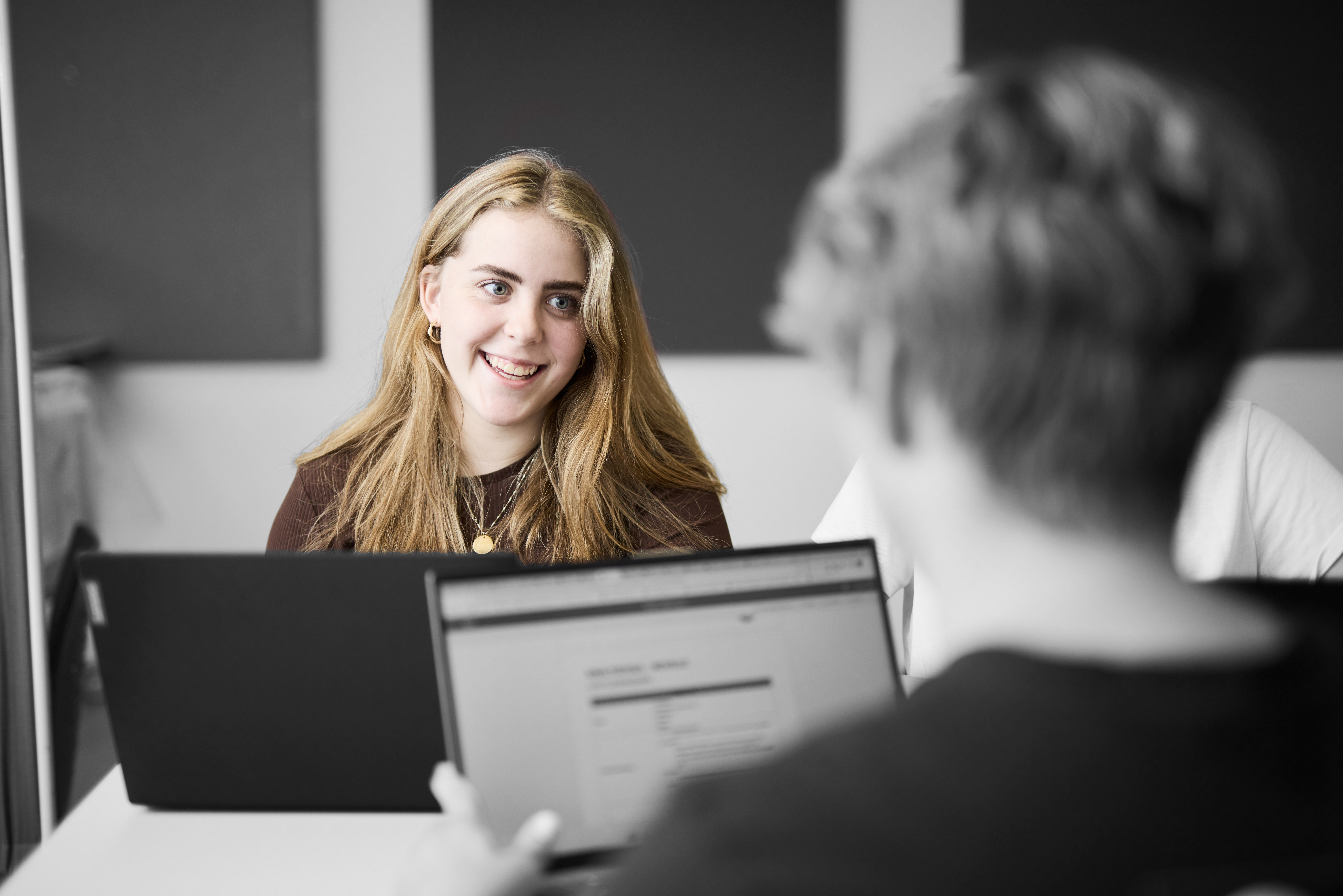 Pædagogisk assistent sidder ved et bord og skal løse en opgave på computeren