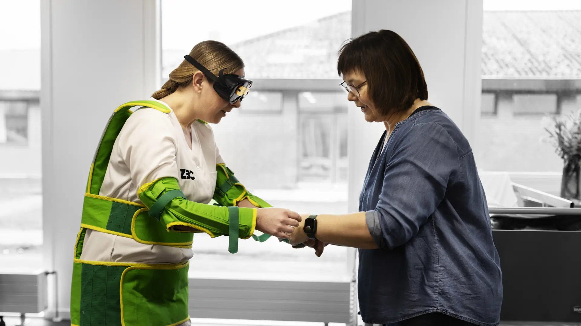 Social- og sundhedsassistent har ældredragt på og får støtte af faglærer