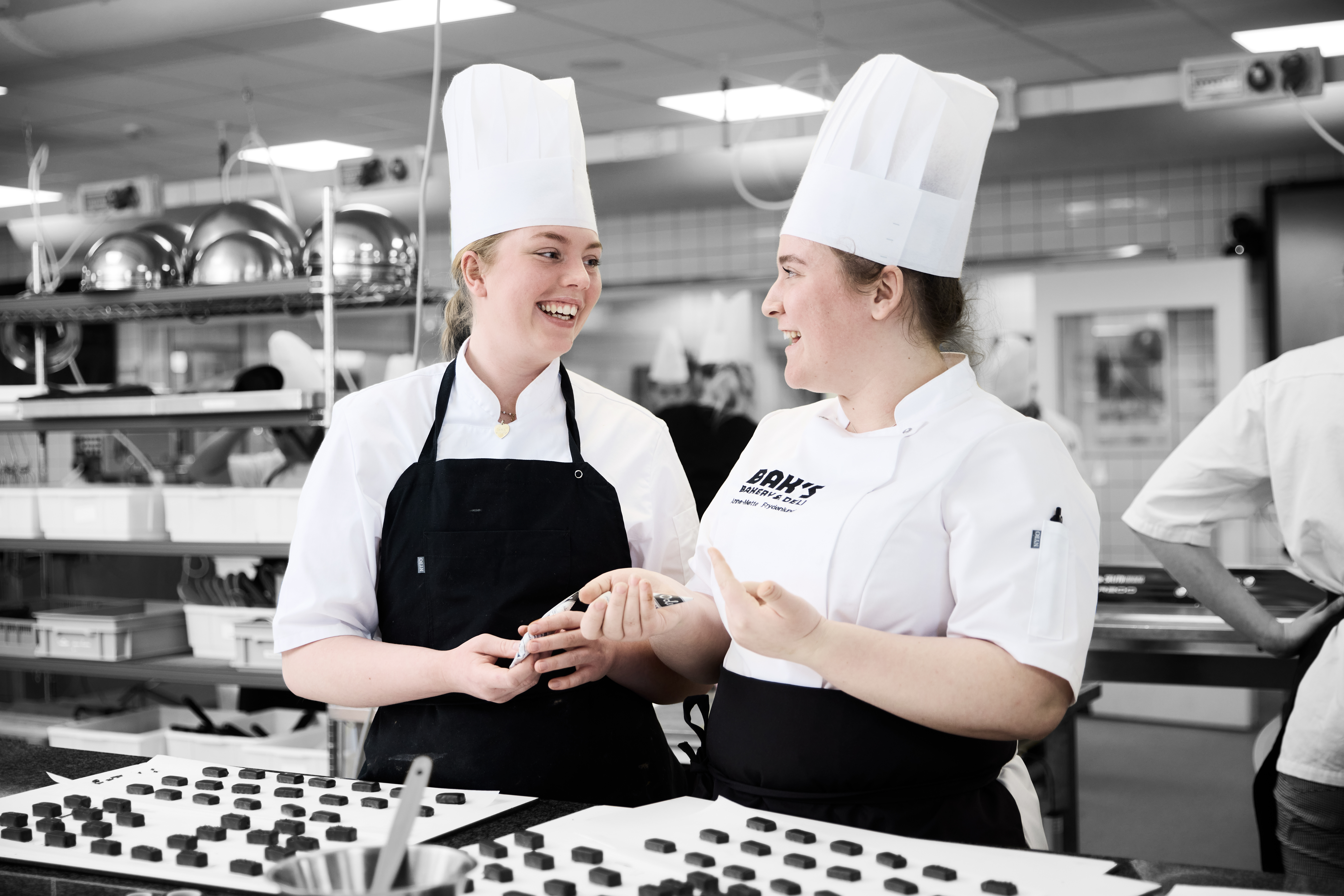 Konditorer i køkken arbejder med fyldte chokolader