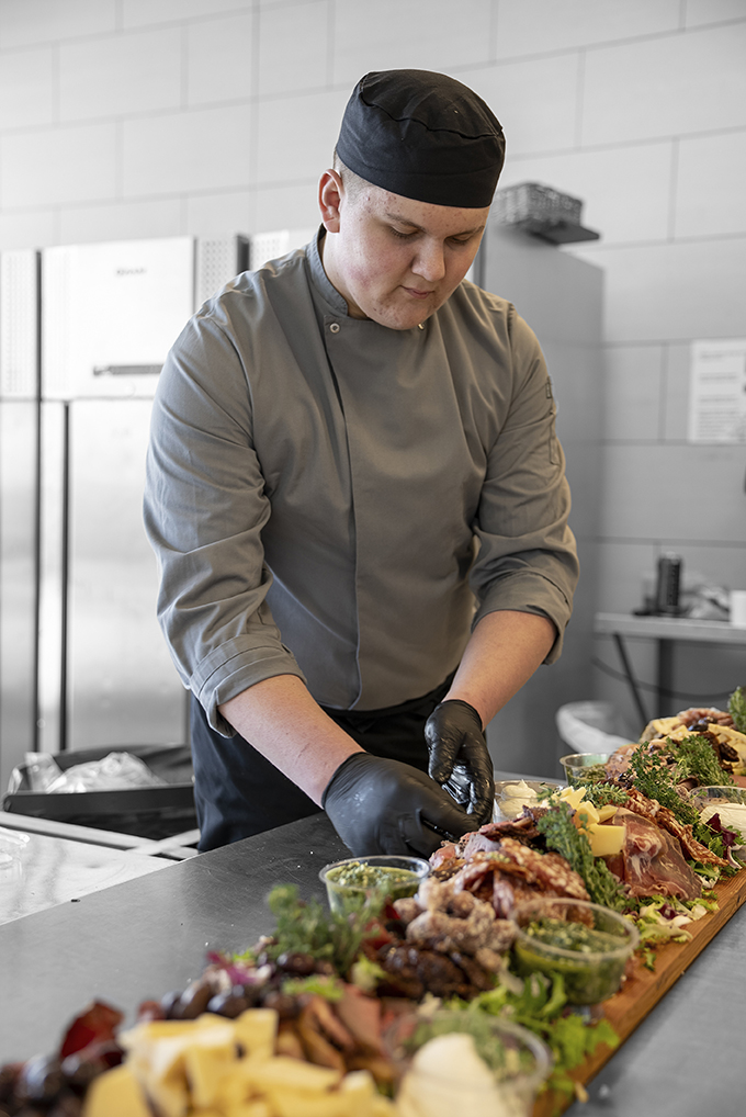 Elev på Gourmetslagteruddannelsen arbejder med mad i køkkenet