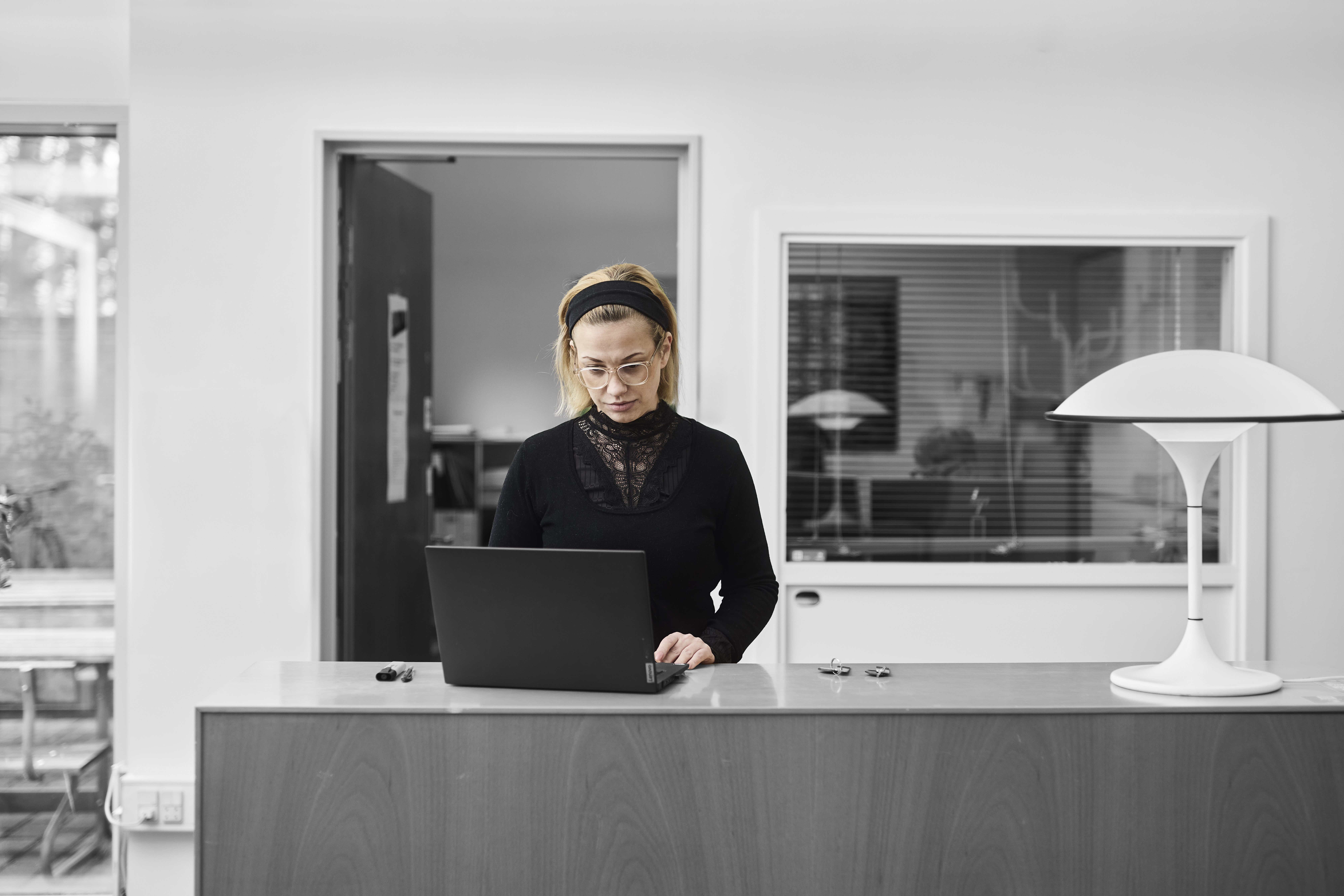 Receptionistelev står ved en skranke og arbejder på computer