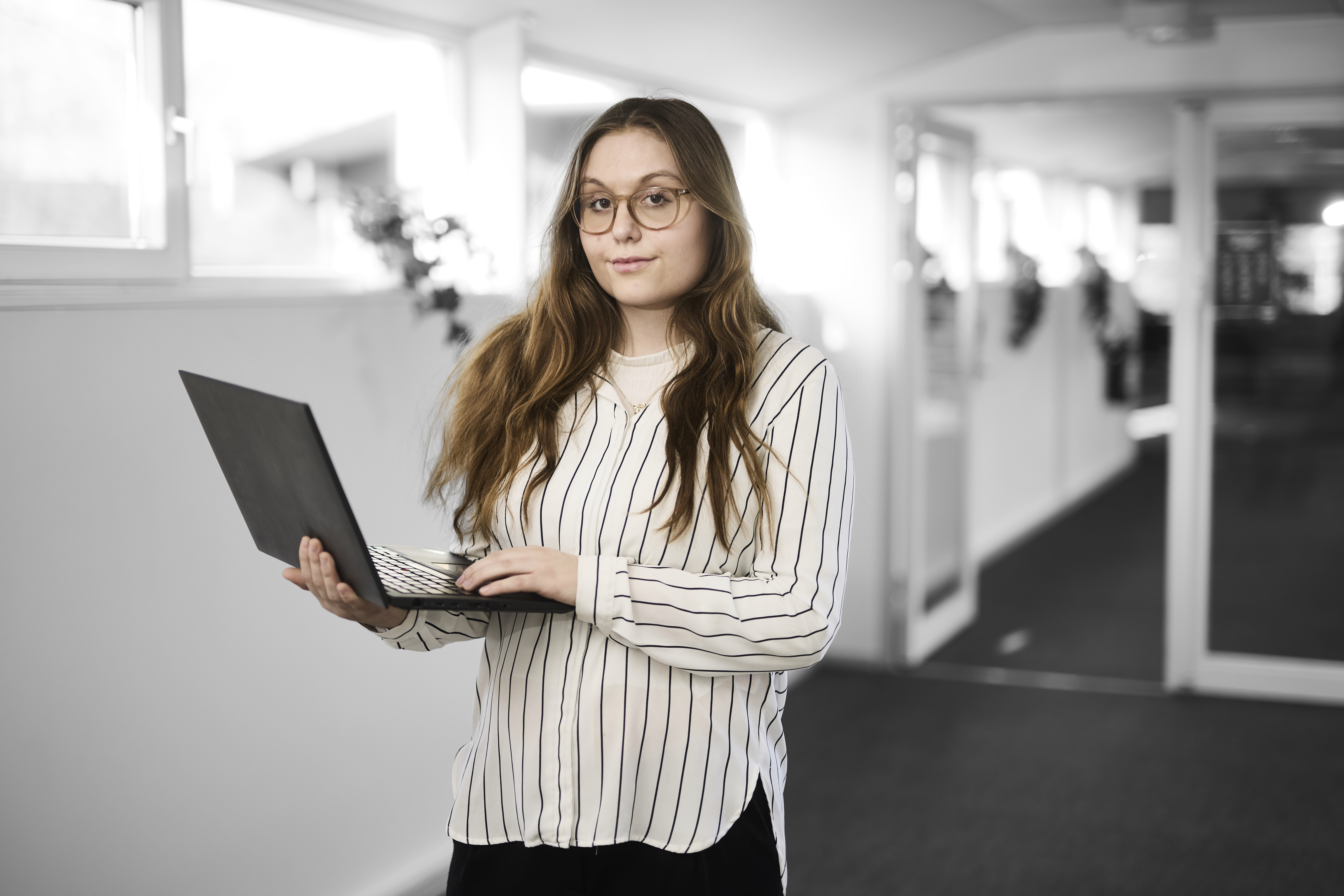 Receptionistelev står med en computer 