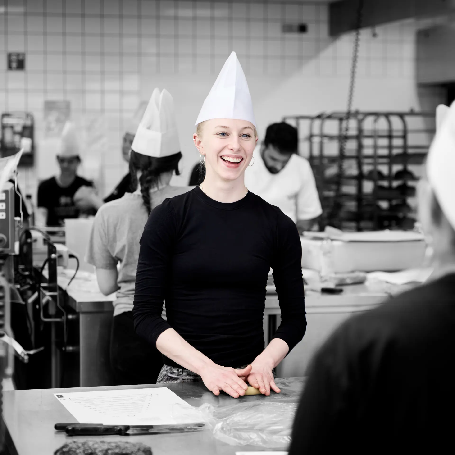 Bager i køkken, mens hun smiler og arbejder med dej