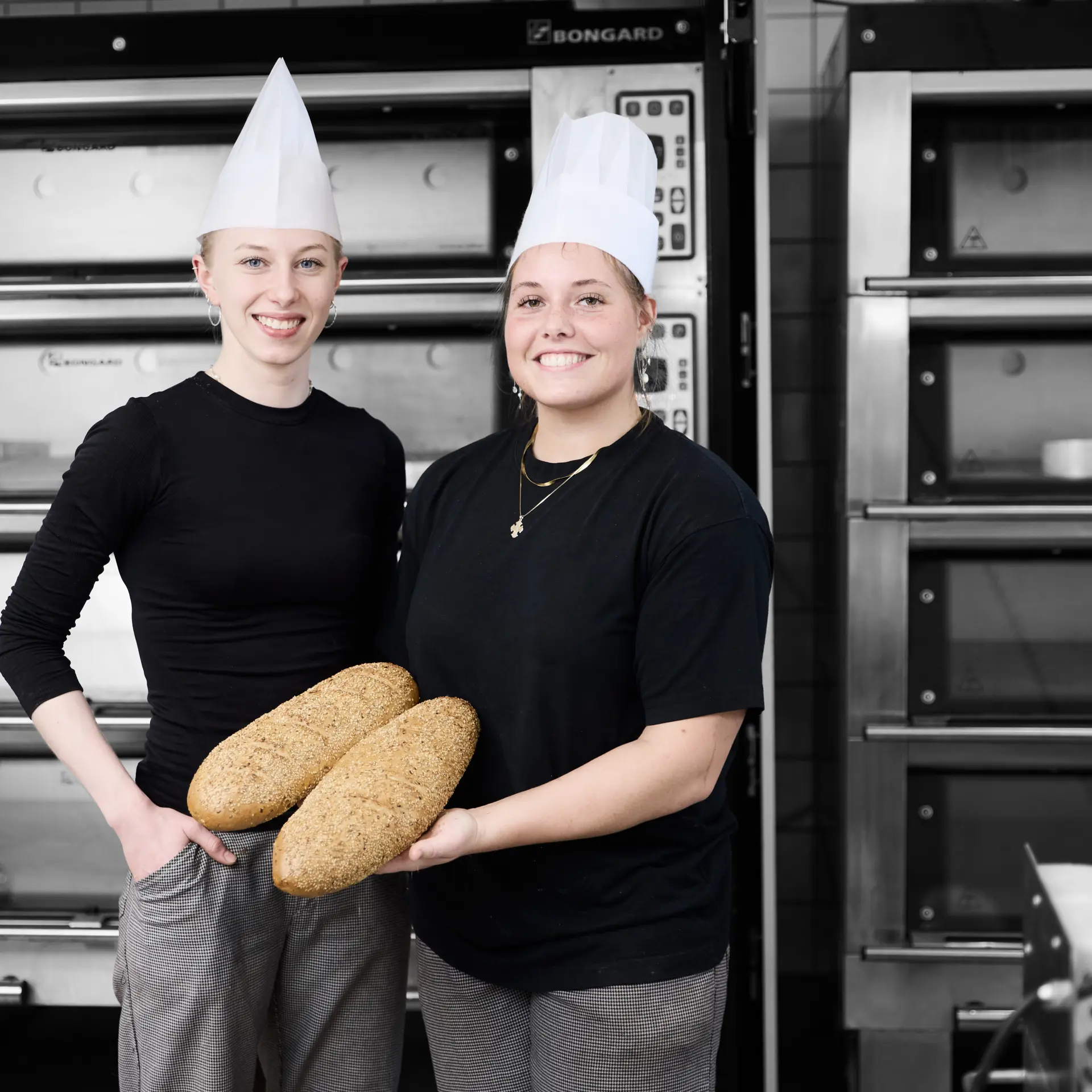 Bagere med brød, mens de står foran en masse ovne