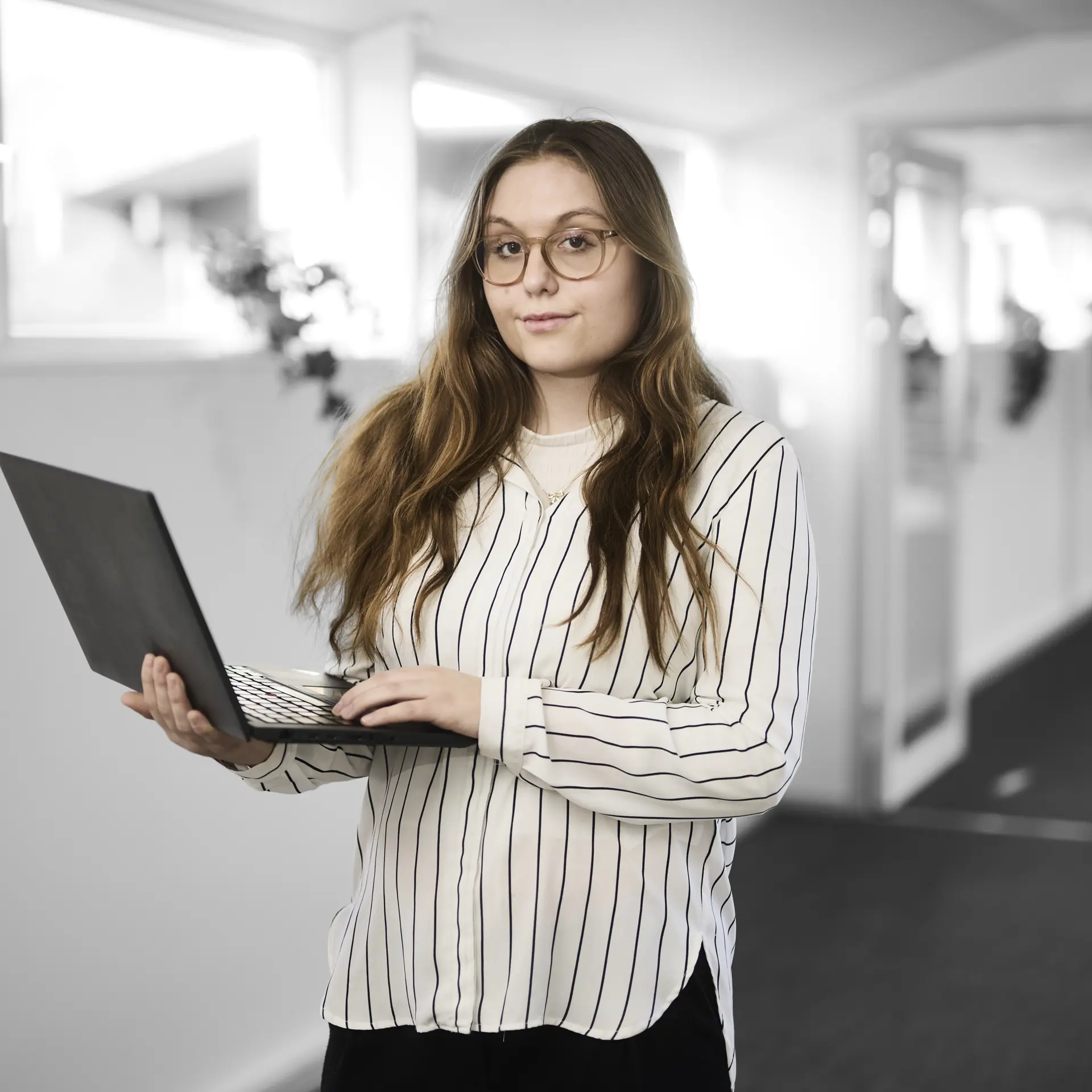 Receptionistelev står med en computer